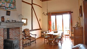 A dining area with a brick fireplace, wooden chairs, a table, and a chandelier. - Sommette (Somme-Leuze)