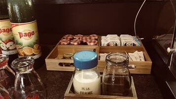 Un comptoir de cuisine avec divers aliments et condiments, notamment des bouteilles de jus de fruits, des pots de miel et une boîte en bois étiquetée « PRODUITS LAITIERS ».