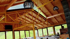 A spacious dining area with wooden beams, large windows, and a high ceiling. Tables are set with white tablecloths and chairs. - Ayderoom Otel (Camlihemsin)