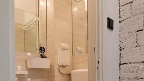 A modern bathroom with a toilet, a glass shower enclosure, and a white brick accent wall. - Bizzi LuxProchnika Studio (Warsaw)