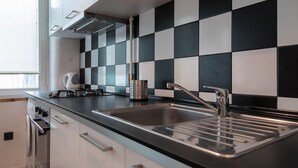 A modern kitchen with a black and white checkered backsplash, stainless steel sink, and built-in oven. - Bizzi LuxProchnika Studio (Warsaw)