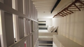 Habitación de hotel moderna con una escalera, una cama con ropa de cama blanca y un perchero de madera.