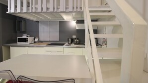 Cocina compacta con microondas, tostadora y cafetera sobre la encimera.