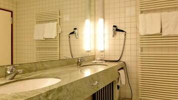 A bathroom with a large sink, a mirror, and towel racks.