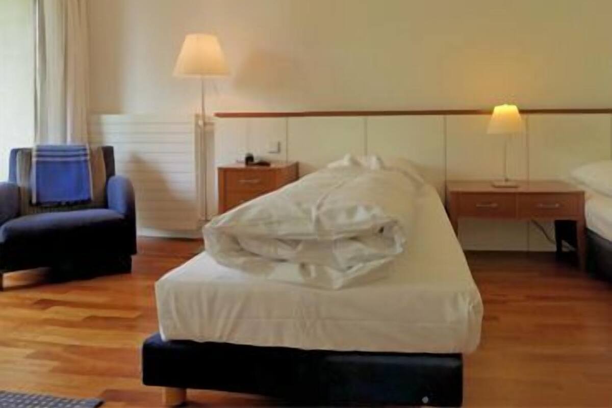 Une chambre d’hôtel avec un lit, une chaise, un bureau et une lampe.