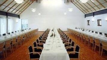 A conference room with a long table and chairs, high ceilings, and large windows.