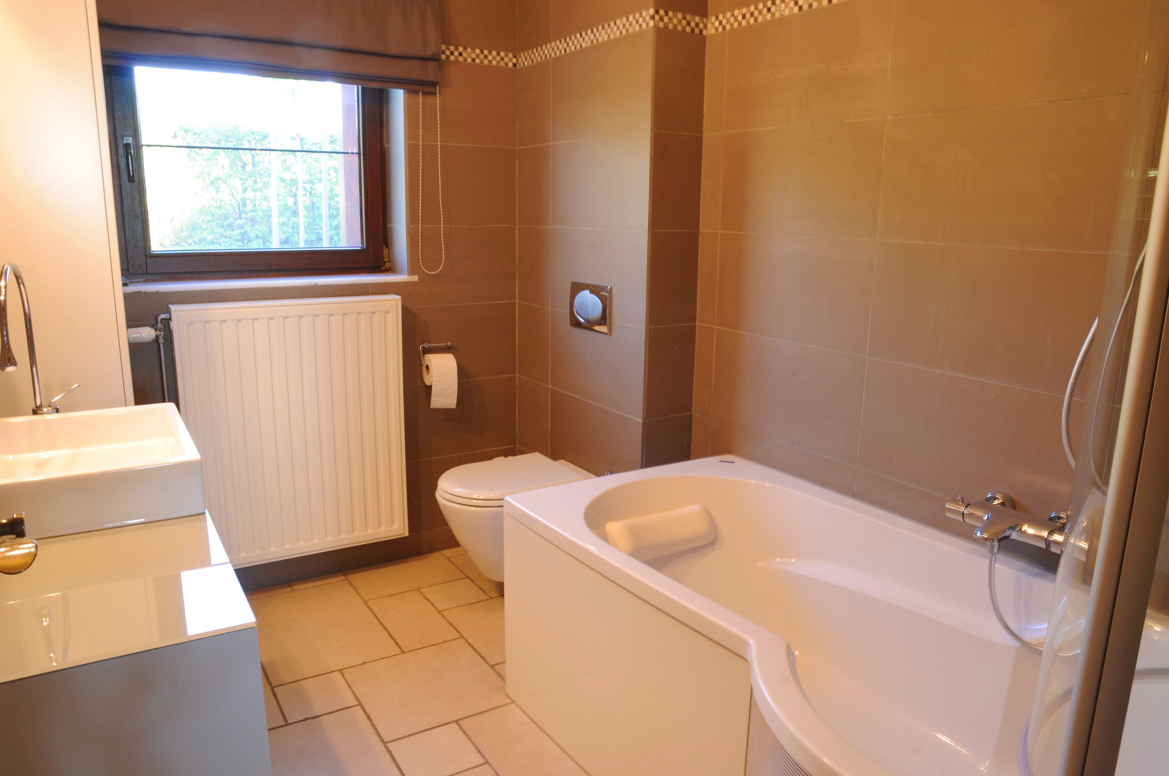 A bathroom with a bathtub, toilet, and window.