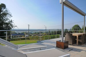 A terrace with a table and chairs, a wooden planter, and a view of the landscape.