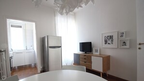 A modern kitchen with a refrigerator, a dining table, and a TV on a wooden cabinet. - Italianway   - Piacenza (Milan)