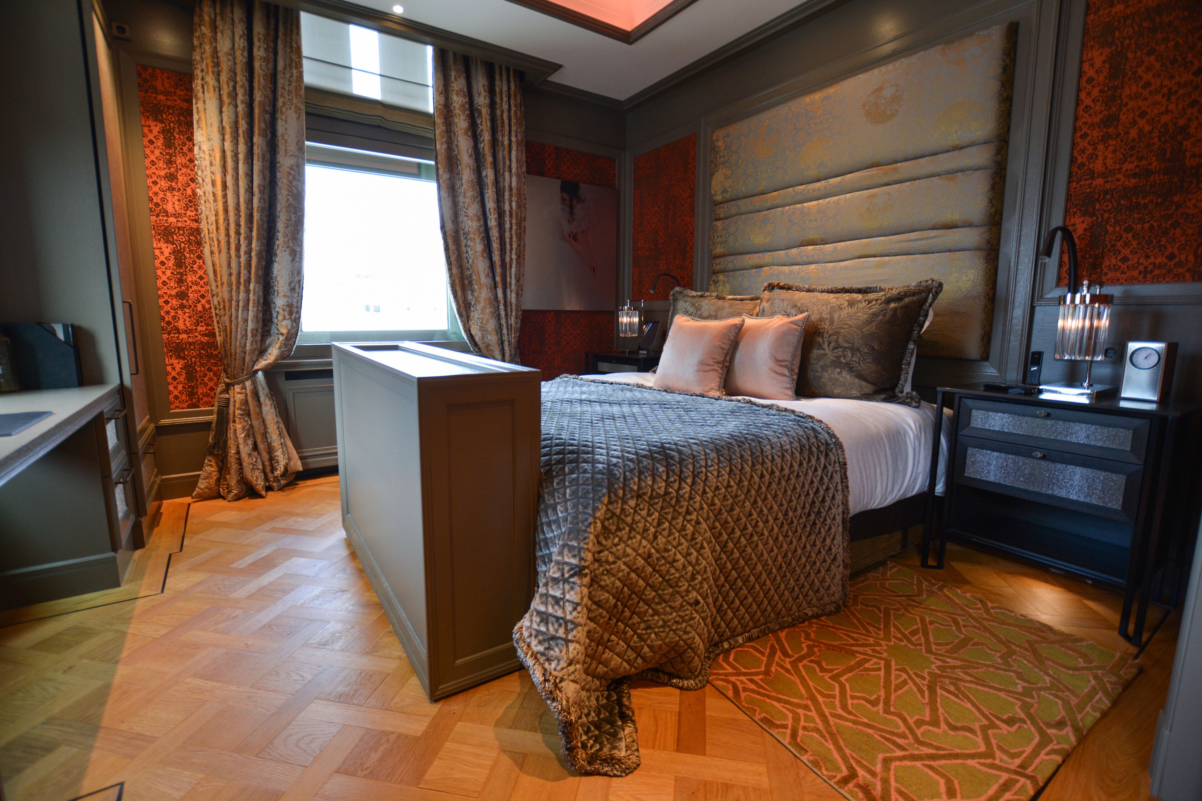 A modern hotel room with a large bed, a desk, and a nightstand.