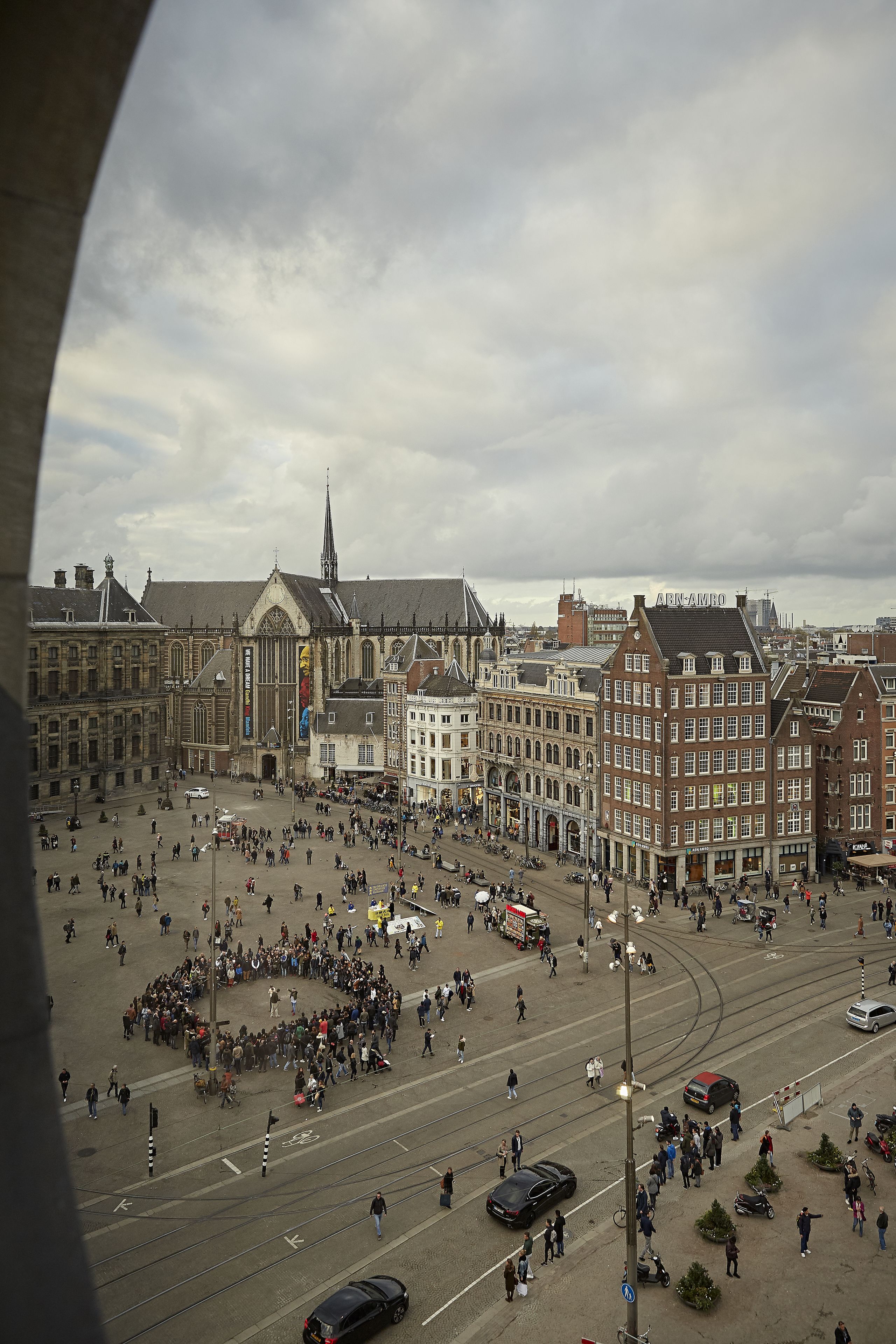 A historic square with a prominent church and adjacent buildings, surrounded by a crowd.