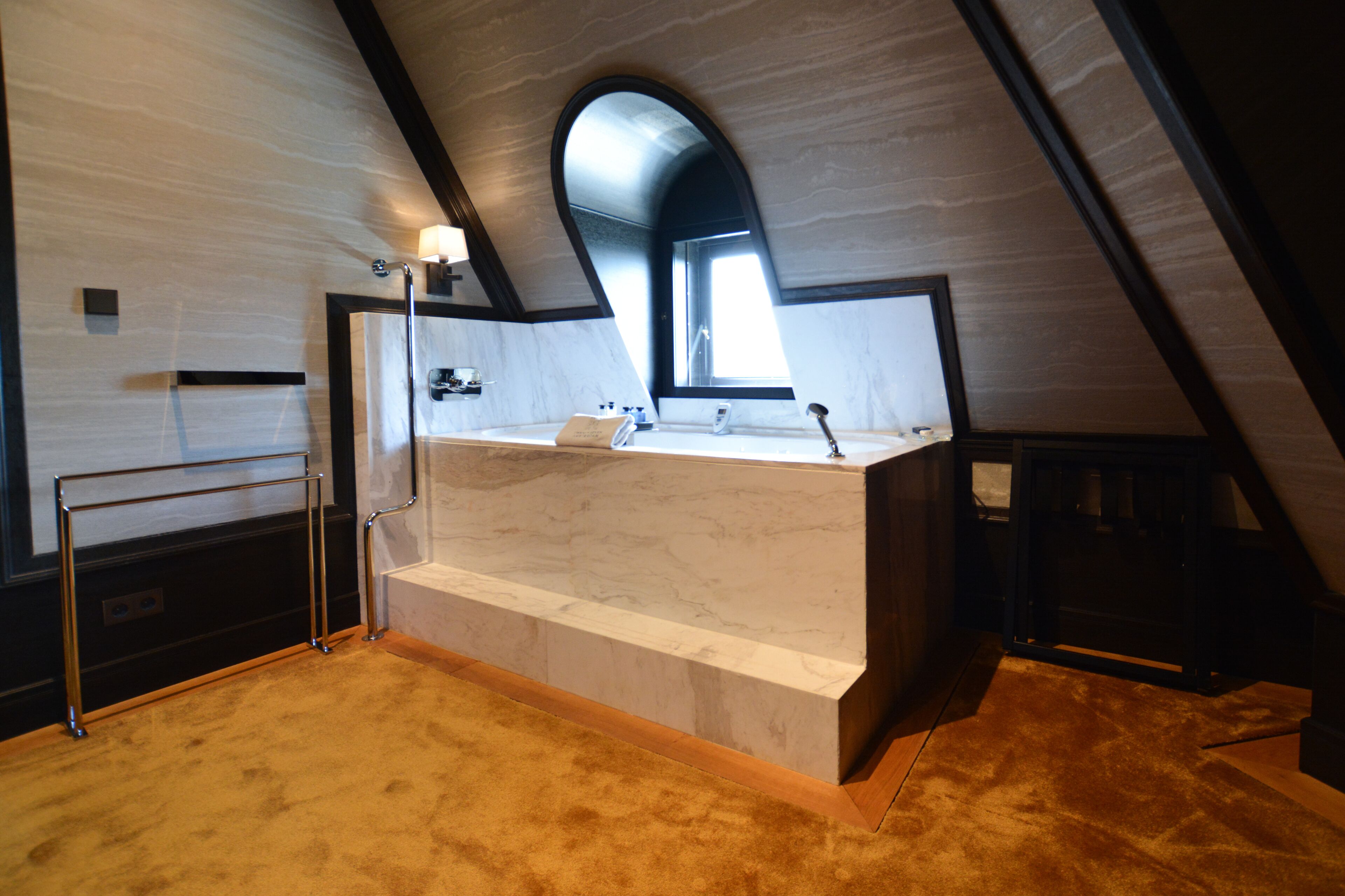 A bathroom with a marble sink, a towel rack, and a window.