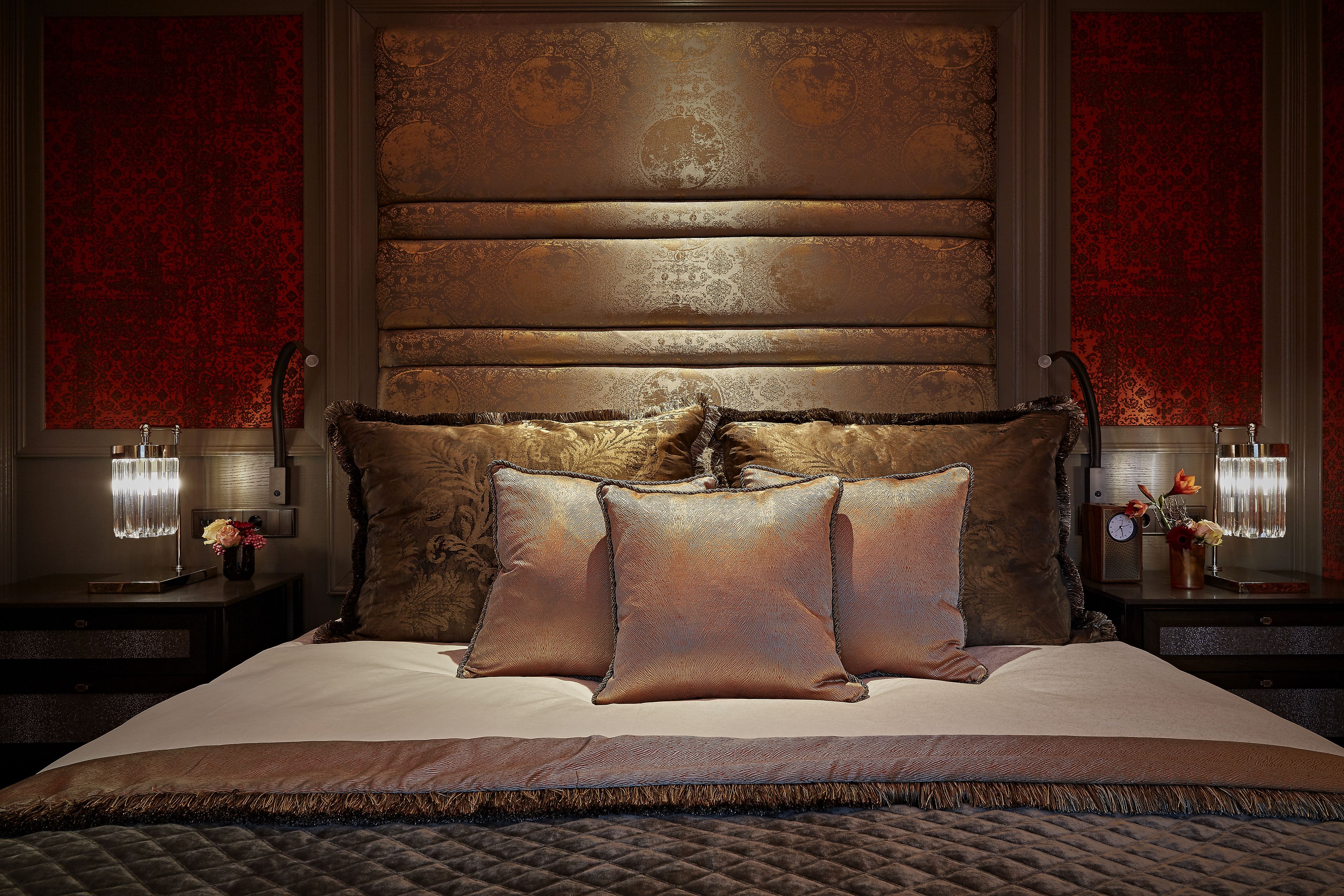 A bed with a quilted cover, two nightstands with lamps, and a wall with a textured pattern.