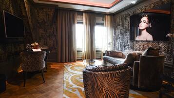 A modern living room with a patterned rug, a sofa, a chair, and a flat-screen TV mounted on the wall.