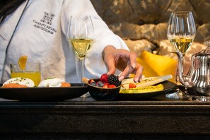 Una mesa de comedor con diversos alimentos, entre ellos, un tazón de bayas mixtas, una copa de vino blanco y un plato con un sándwich.