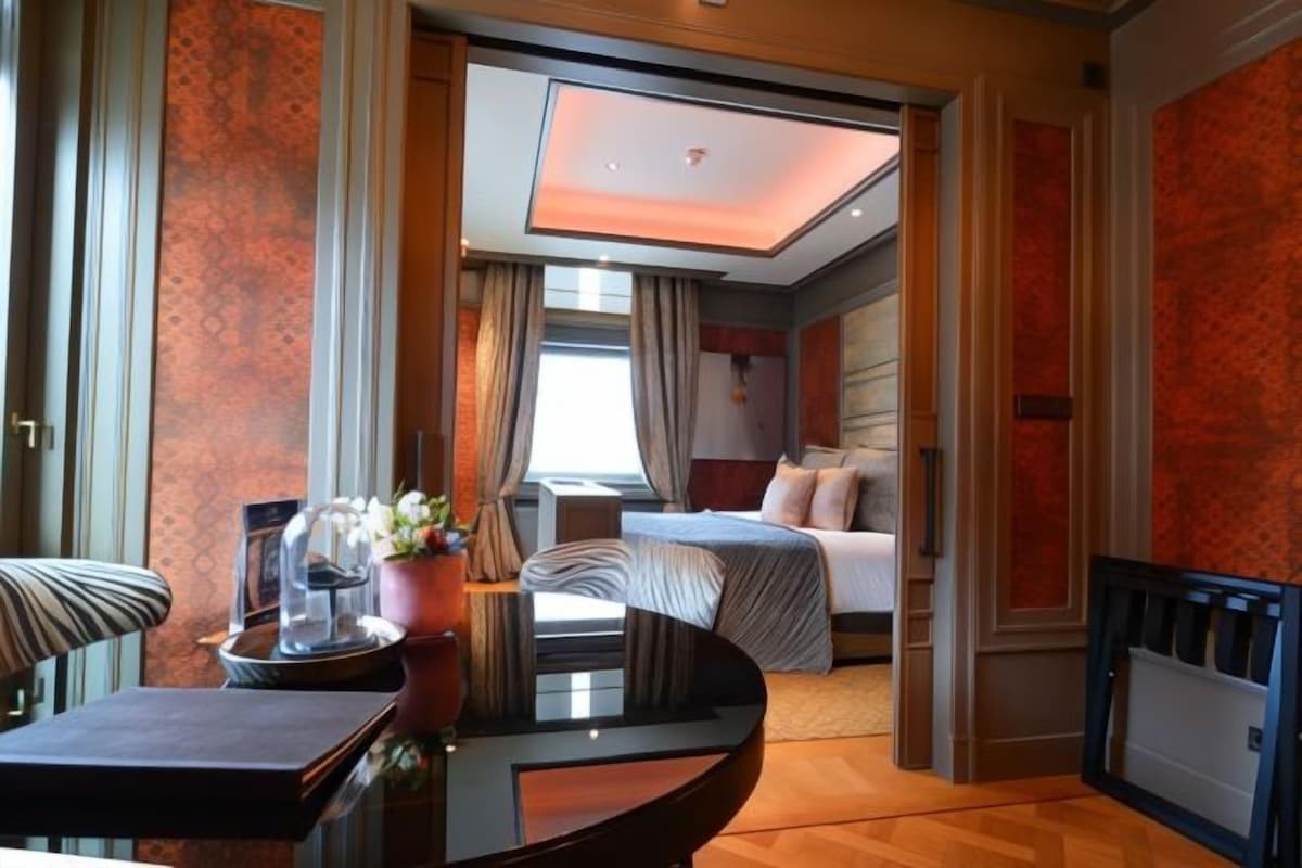 A hotel room with a bed, a desk, a chair, and a view of the city.