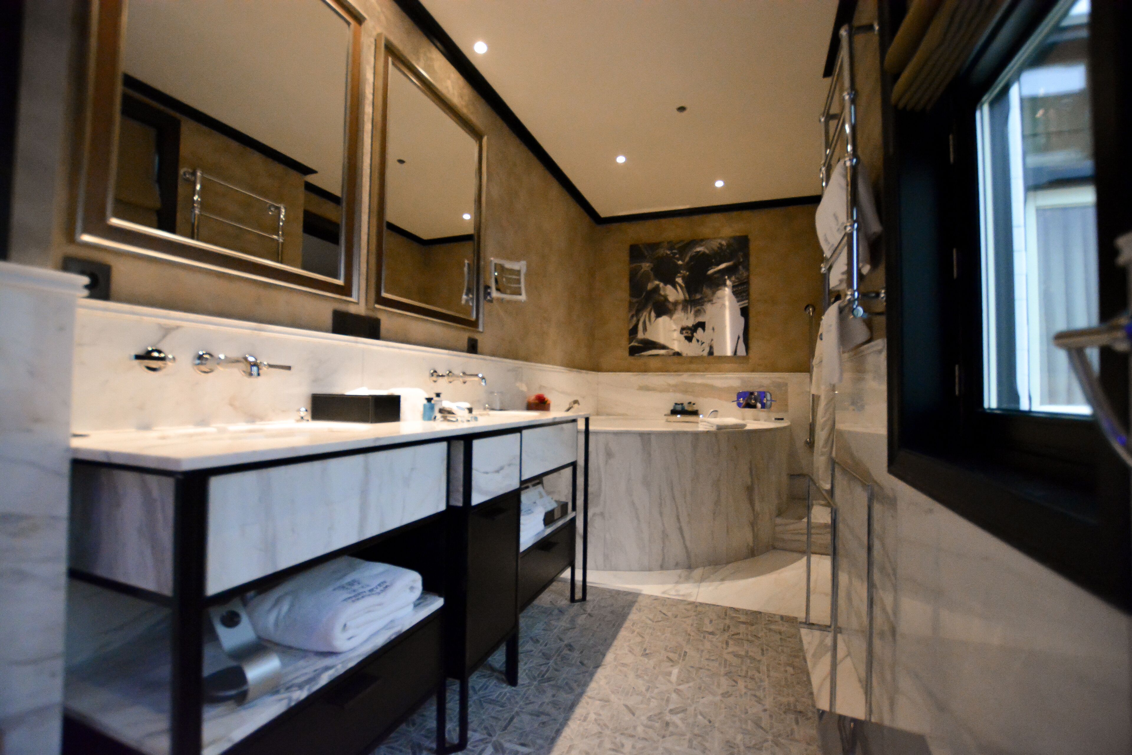 Ein modernes Badezimmer mit einem großen Spiegel, zwei Waschbecken, einer Badewanne und einer Dusche.