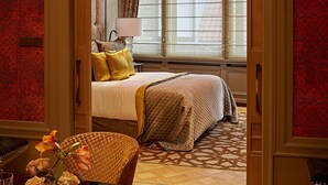 Habitación de hotel con cama, escritorio y una silla. Cuenta con una ventana con cortinas y una lámpara en el escritorio.