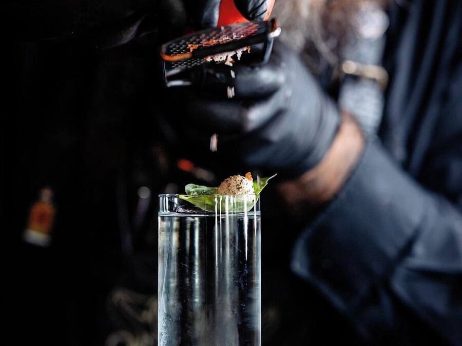 A bartender pouring a drink into a tall glass.