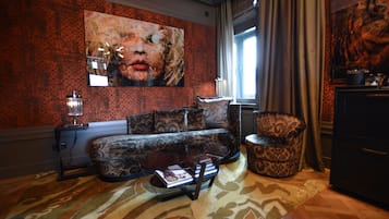 A living room with a patterned sofa, a coffee table, and a large painting on the wall.