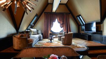 A cozy, triangular room with a sofa, chairs, a coffee table, and a television.