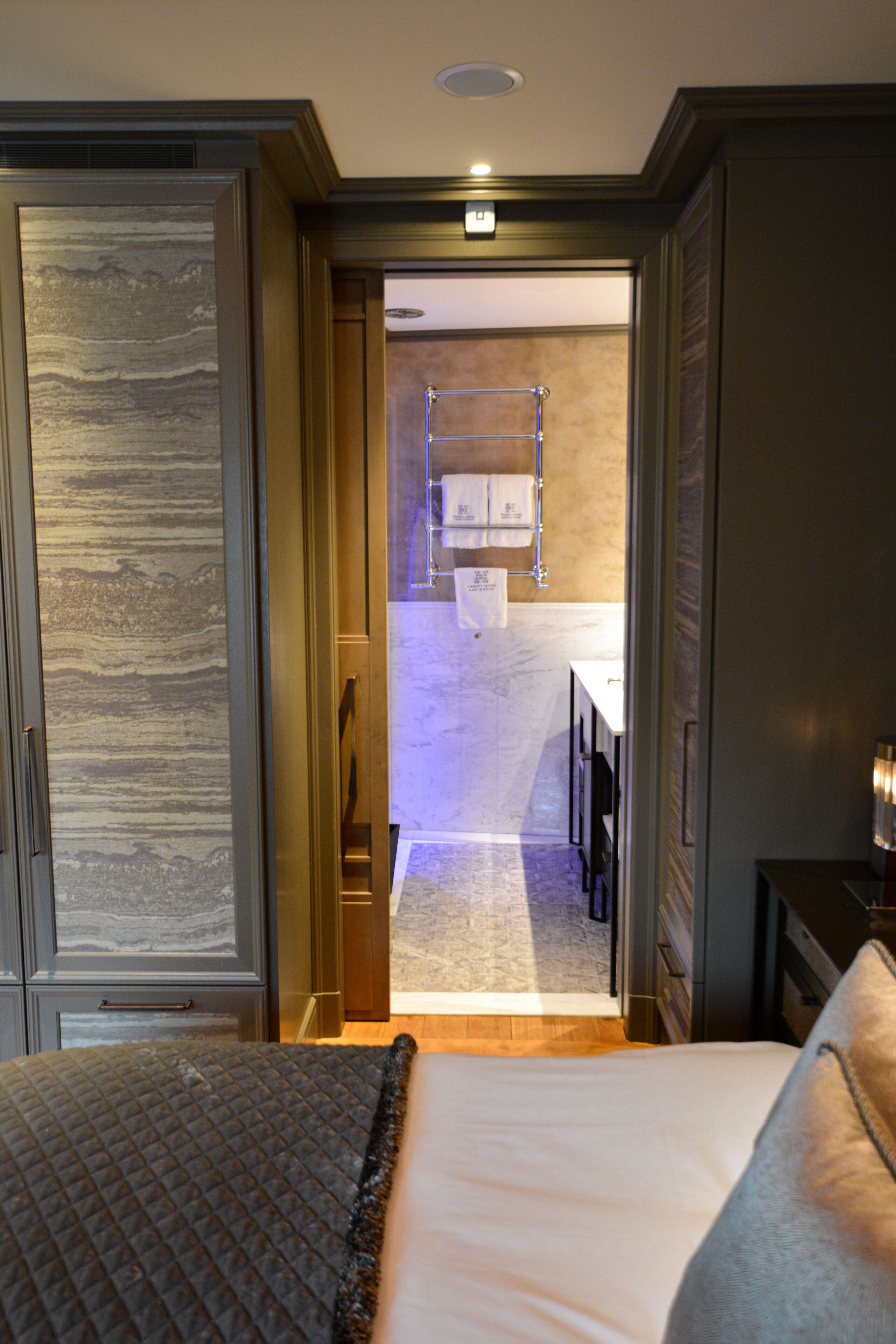 Una habitación de hotel con una cama, una mesita de noche y vistas al baño.