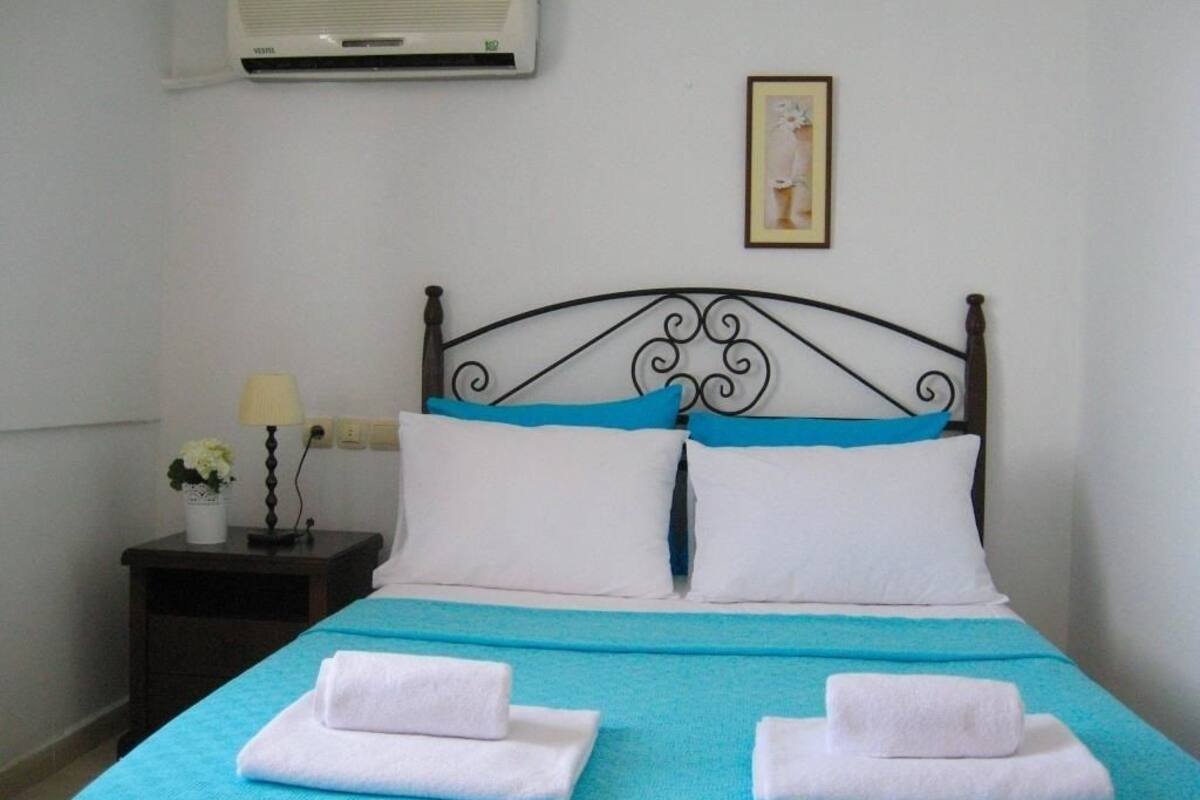 A bed with a blue bedspread, white pillows, and two folded towels.