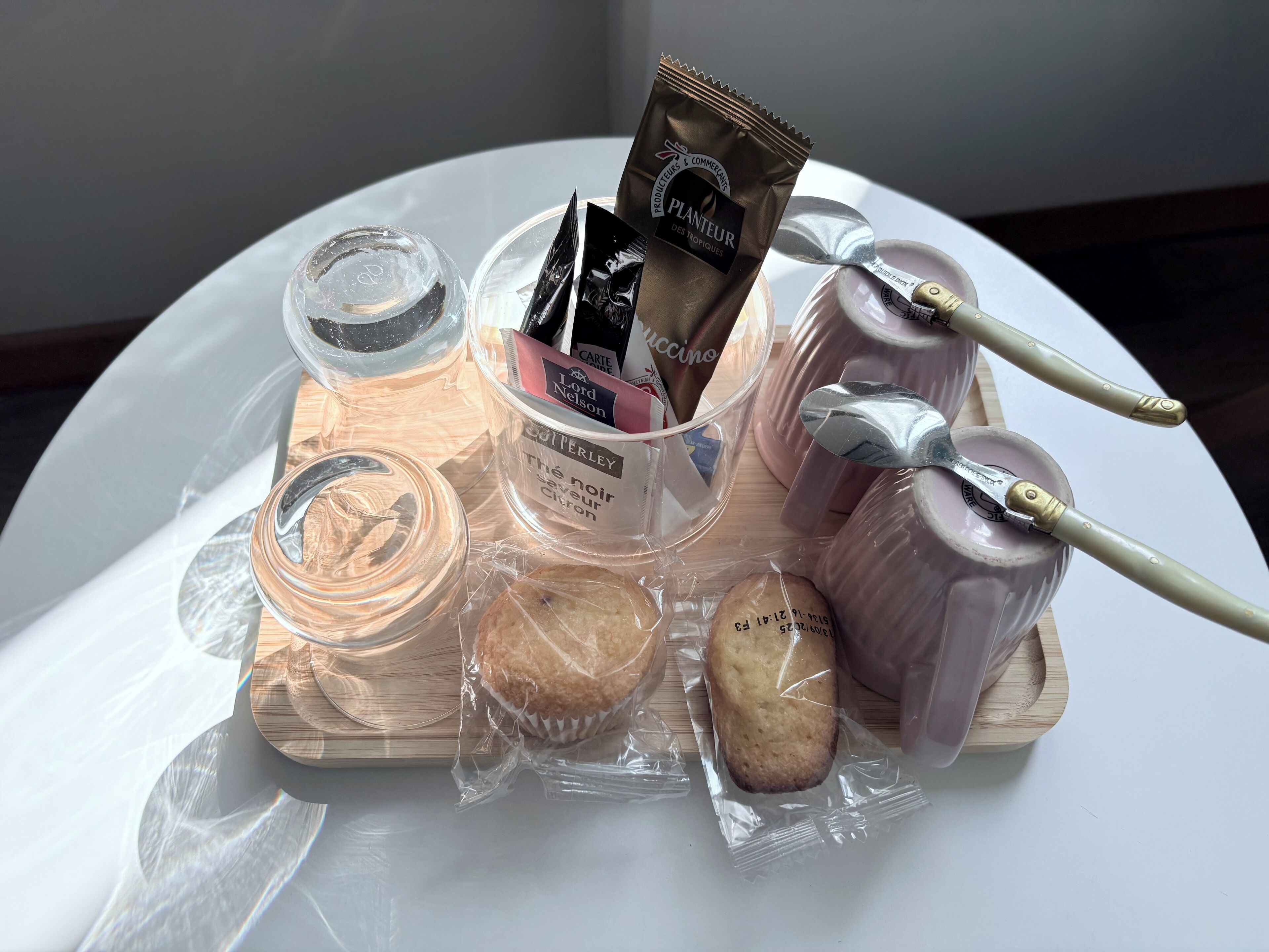 A tray with various packaged items including a bottle of perfume, a jar of honey, a packet of tea, and a small wooden object.