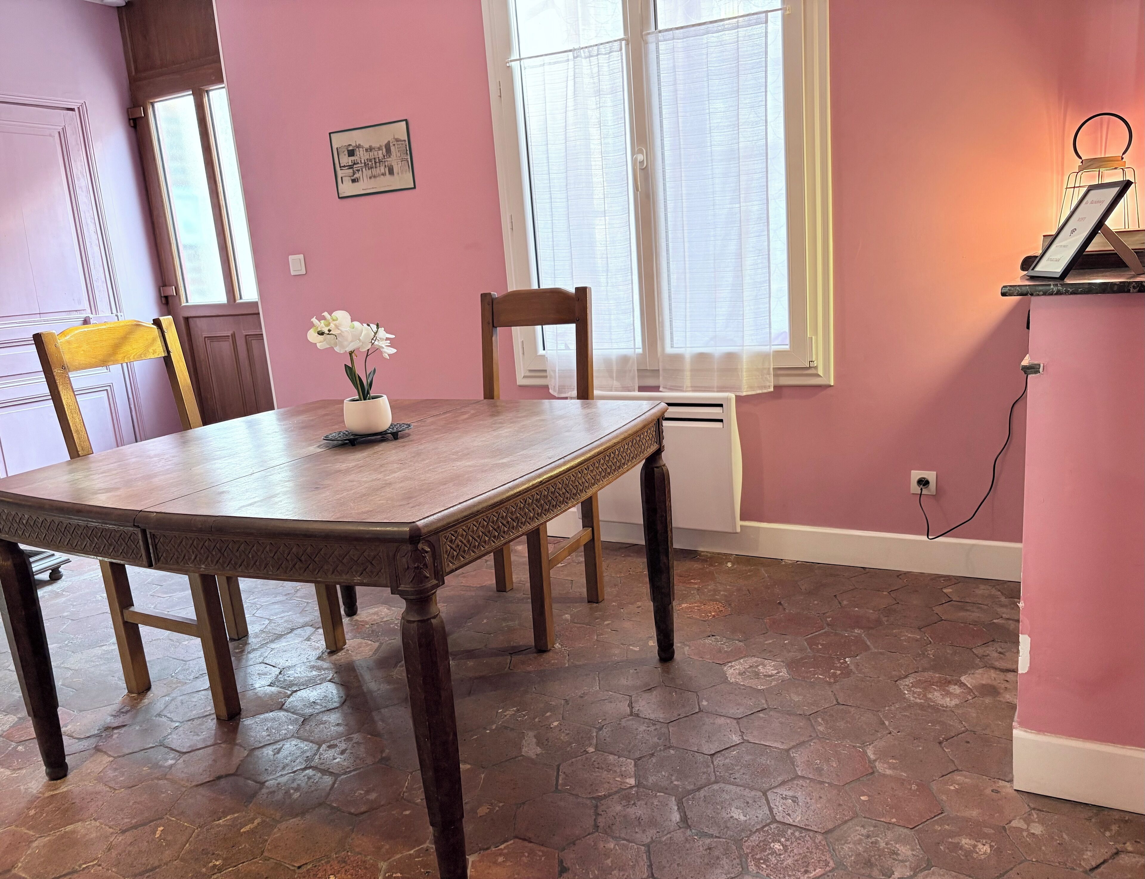 A dining area with a wooden table, chairs, and a potted orchid.