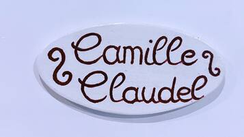 A white oval plaque with the name "Camille Claudel" in brown script.