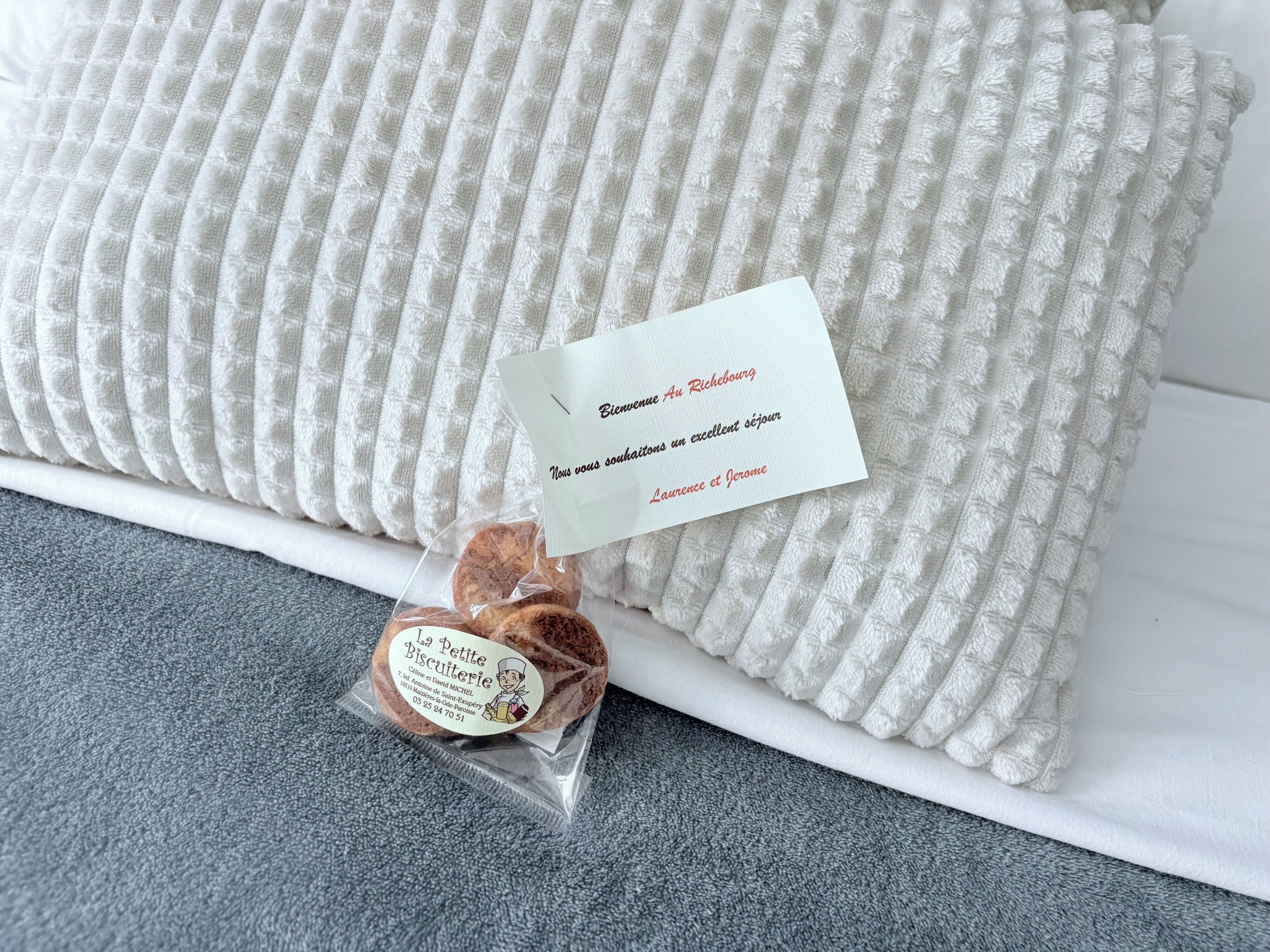 A white textured pillow with a tag and a small package of biscuits.