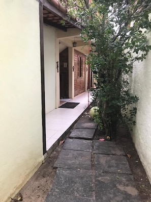 A narrow pathway leading to a building with a tiled entrance and a brick wall. - Pousada Oásis do Barral (Rio de Janeiro)