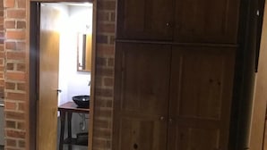 Una habitación con un armario de madera grande, suelo de baldosas y pared de ladrillo.