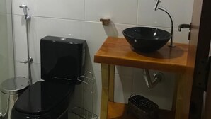 Un baño pequeño con inodoro, bidé y un mueble de tocador de madera con lavamanos y espejo.