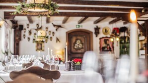 Un espace repas avec des tables dressées pour le dîner, agrémenté de nappes blanches, de verres à vin et d’un centre de table composé de bougies.