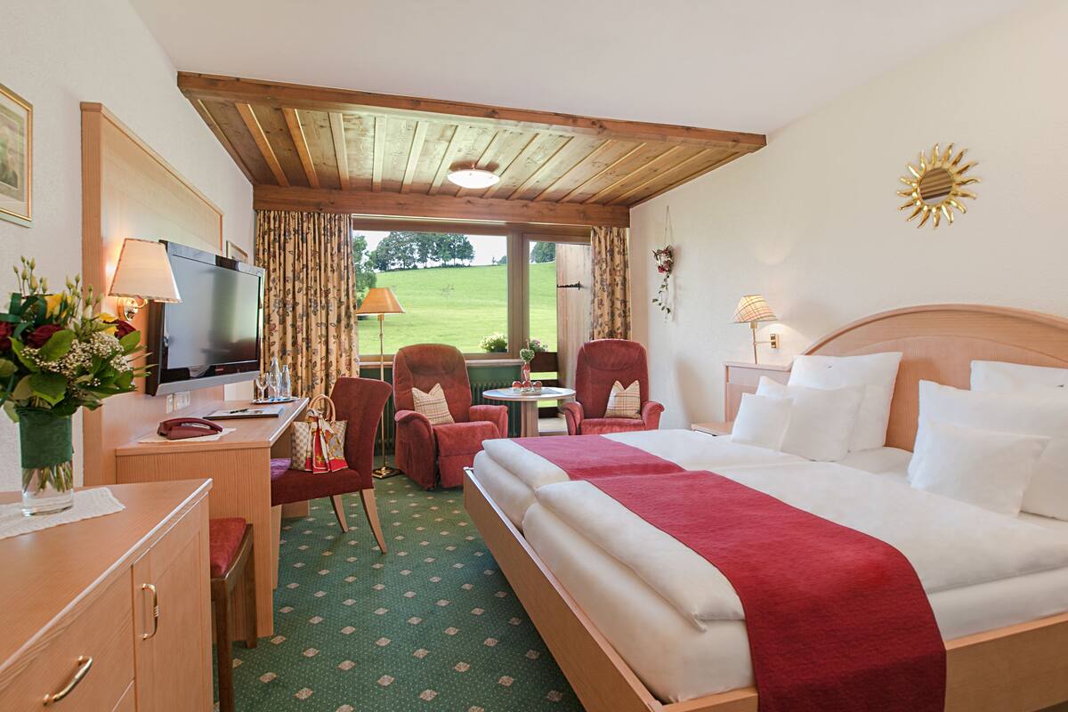 Ein Hotelzimmer mit Bett, Schreibtisch, Stühlen und Fernseher.