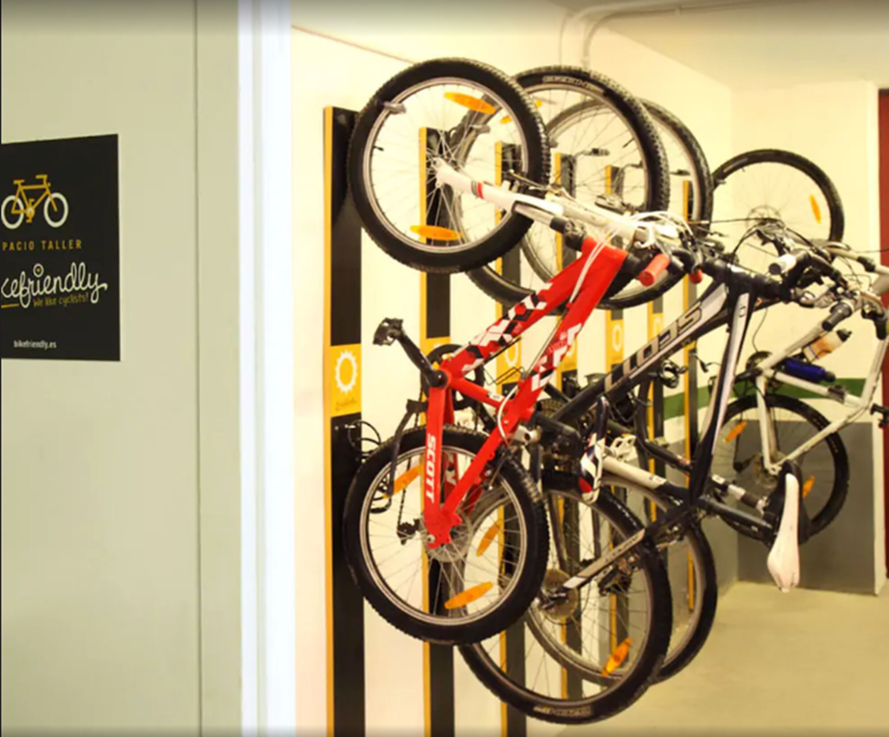 Un'area dedicata al ricovero biciclette, con diverse bici e un cartello che recita 'Biciclette amiche'.