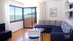 A living room with a large window, a sofa, a TV, and a chair. - Apartamentos Beach & Golf Resort (Pals)