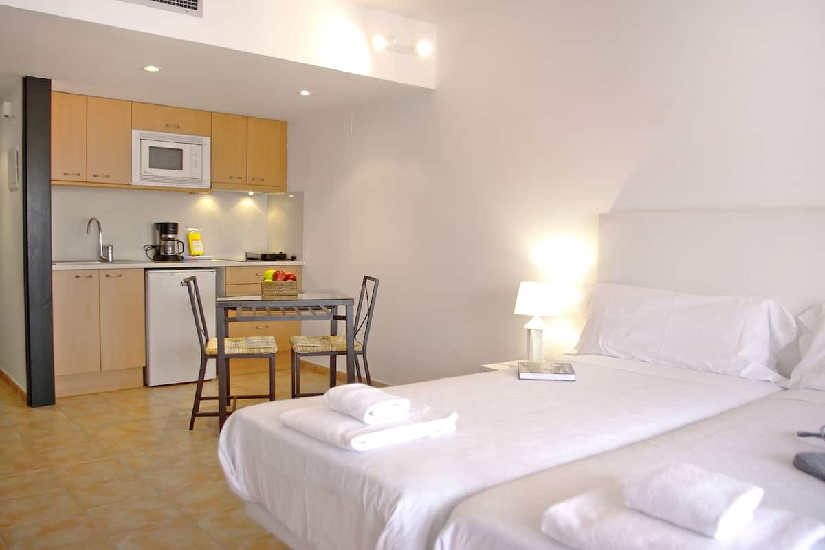 A hotel room with a bed, a desk with a chair, a microwave, a coffee maker, and a sink.