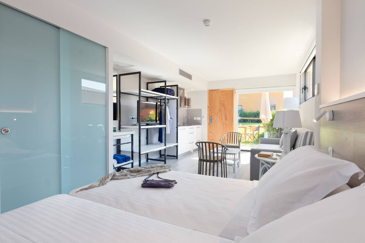 A modern hotel room with a bed, a desk, and a seating area.