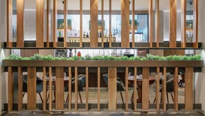 A modern bar area with wooden slats and a green plant top. There are multiple tables and chairs, and a bar counter with bottles. - Sky Blue Hotel & Spa (Paulestii Noi)