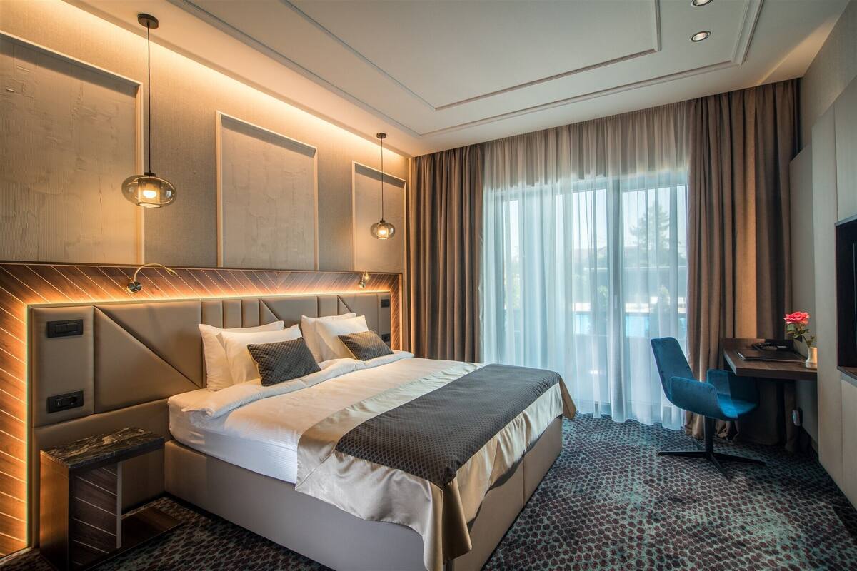 Quarto de hotel moderno com uma cama grande, uma escrivaninha e uma cadeira.