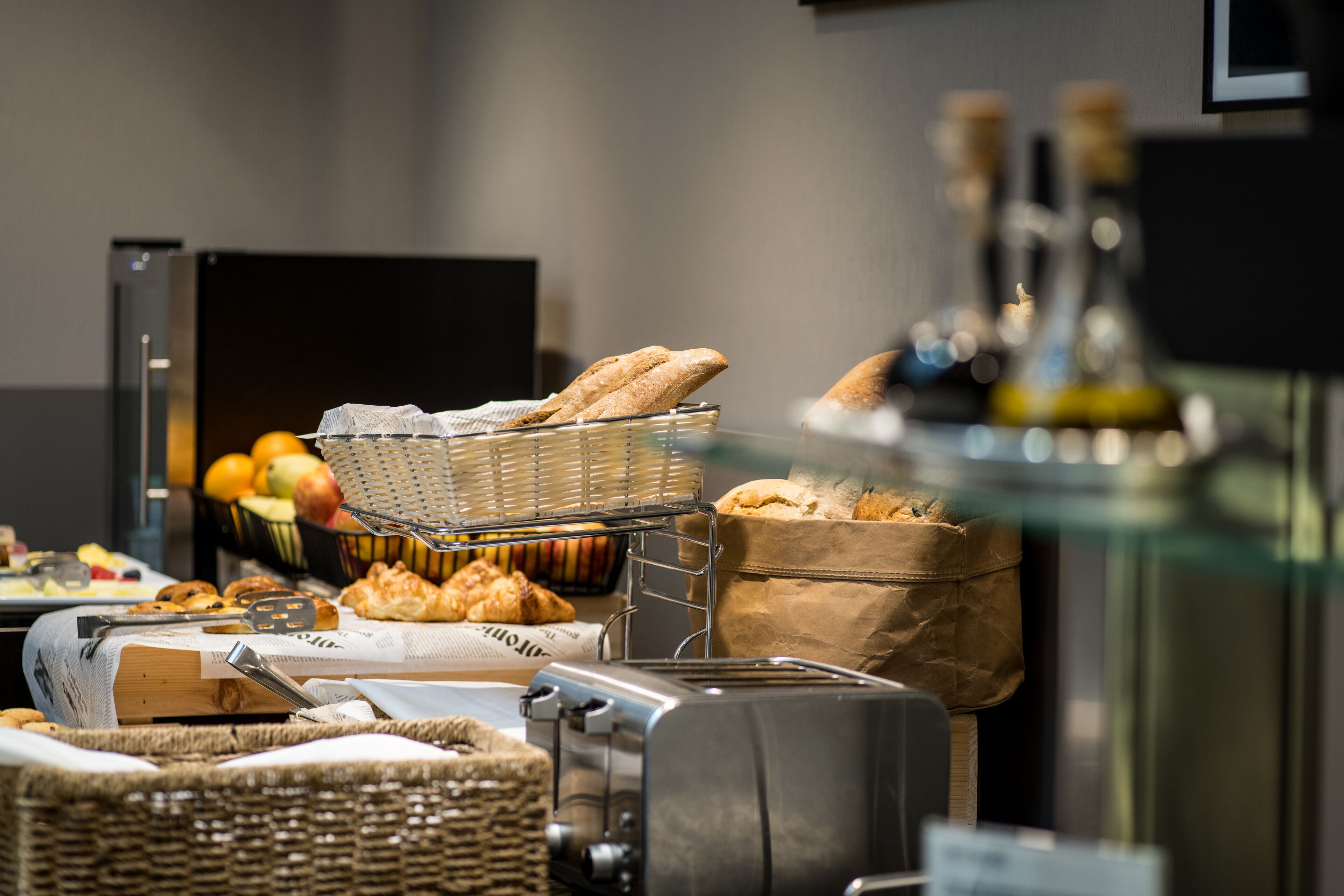 A buffet setup with bread, pastries, and a toaster.