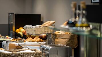 A buffet setup with bread, pastries, and a toaster.