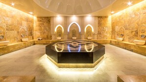 A luxurious bathroom with a central heated floor, multiple sinks, and decorative wall sconces. - Sky Blue Hotel & Spa (Paulestii Noi)