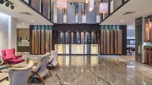A spacious lobby with a high ceiling, modern pendant lighting, and a marble floor. - Sky Blue Hotel & Spa (Paulestii Noi)