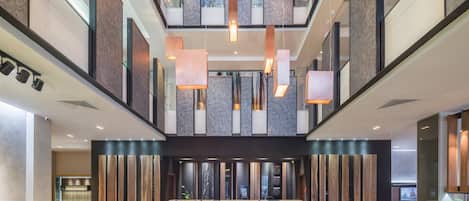 Un hall amplio con techo alto, iluminación colgante moderna y suelo de mármol.