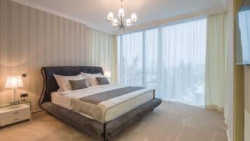 A spacious bedroom with a large bed, a nightstand with a lamp, and a chandelier.