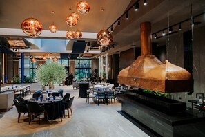 A modern dining area with round tables, chairs, and hanging spherical light fixtures. - Sky Blue Hotel & Spa (Paulestii Noi)