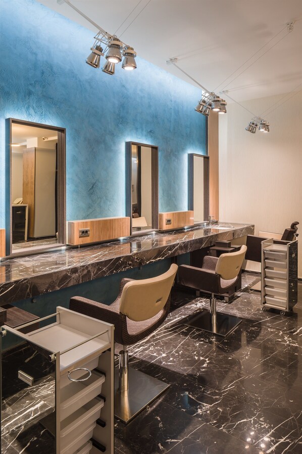 Un baño moderno con encimeras de mármol, varios lavamanos e iluminación empotrada.